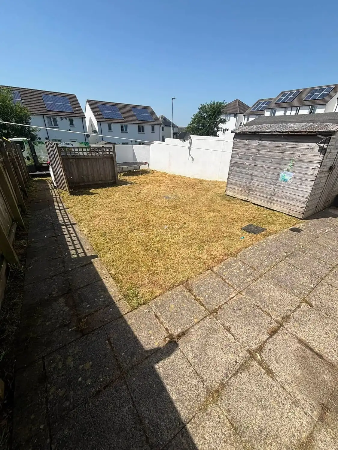 A back garden freshly cut and cleared, with the patio swept and the shed clear again