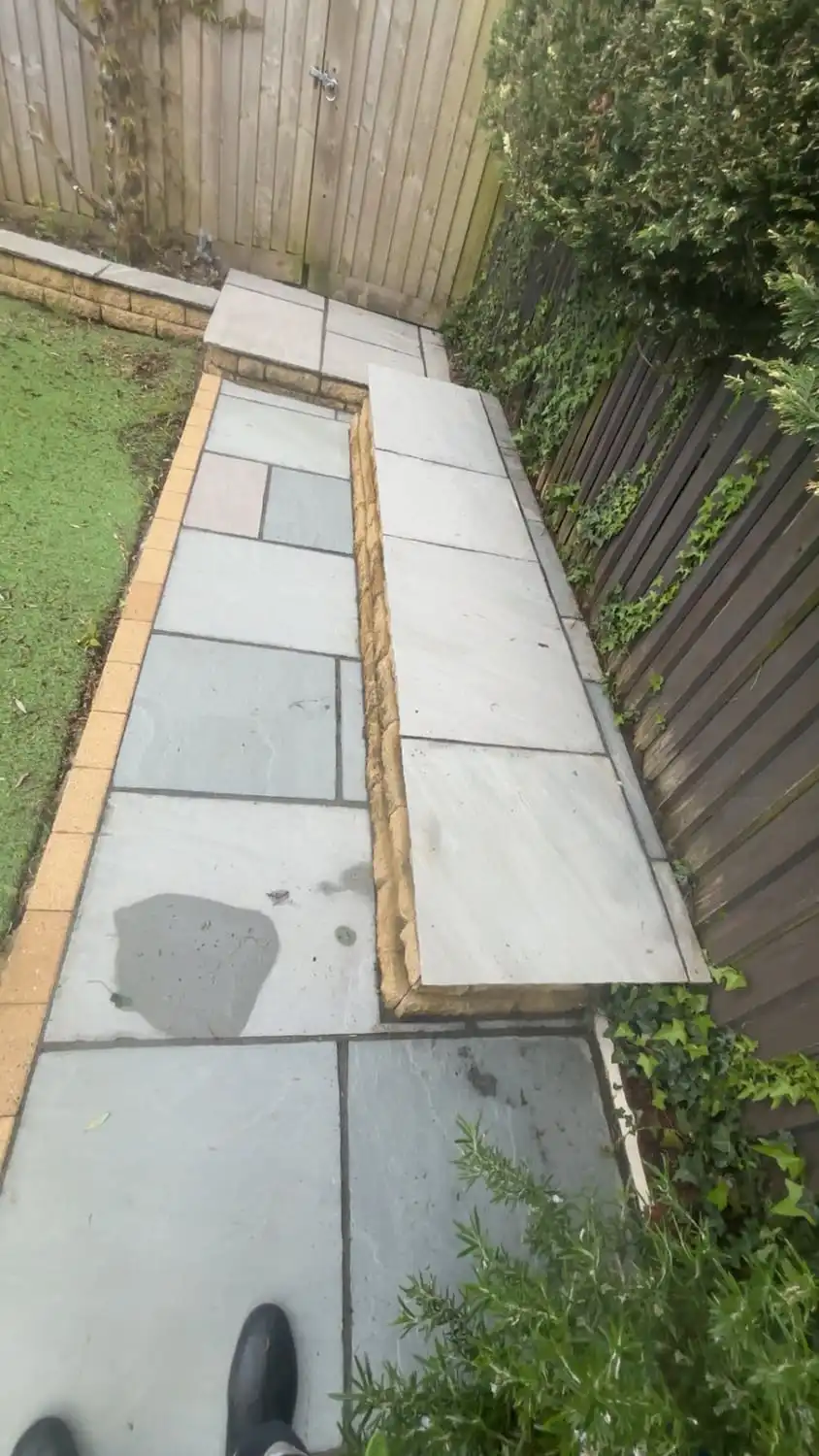 The same path washed back to clean pale slabs with the border cleared and fresh timber edging down