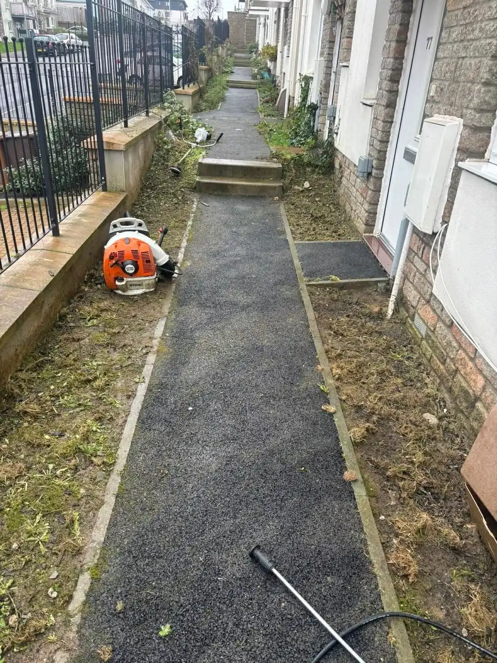 The same path with both edges cut back clean and the surface cleared, blower standing on it