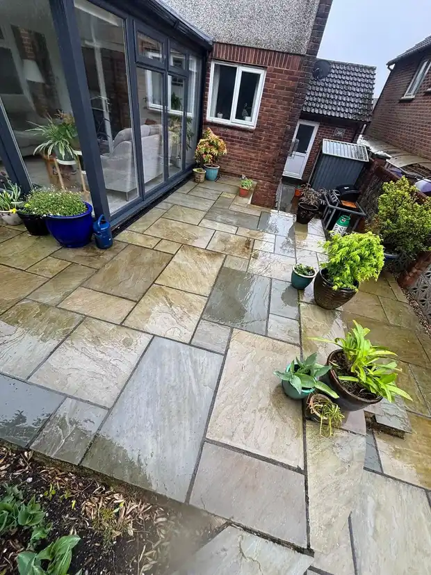 A large sandstone patio washed back to clean stone outside a set of bifold doors