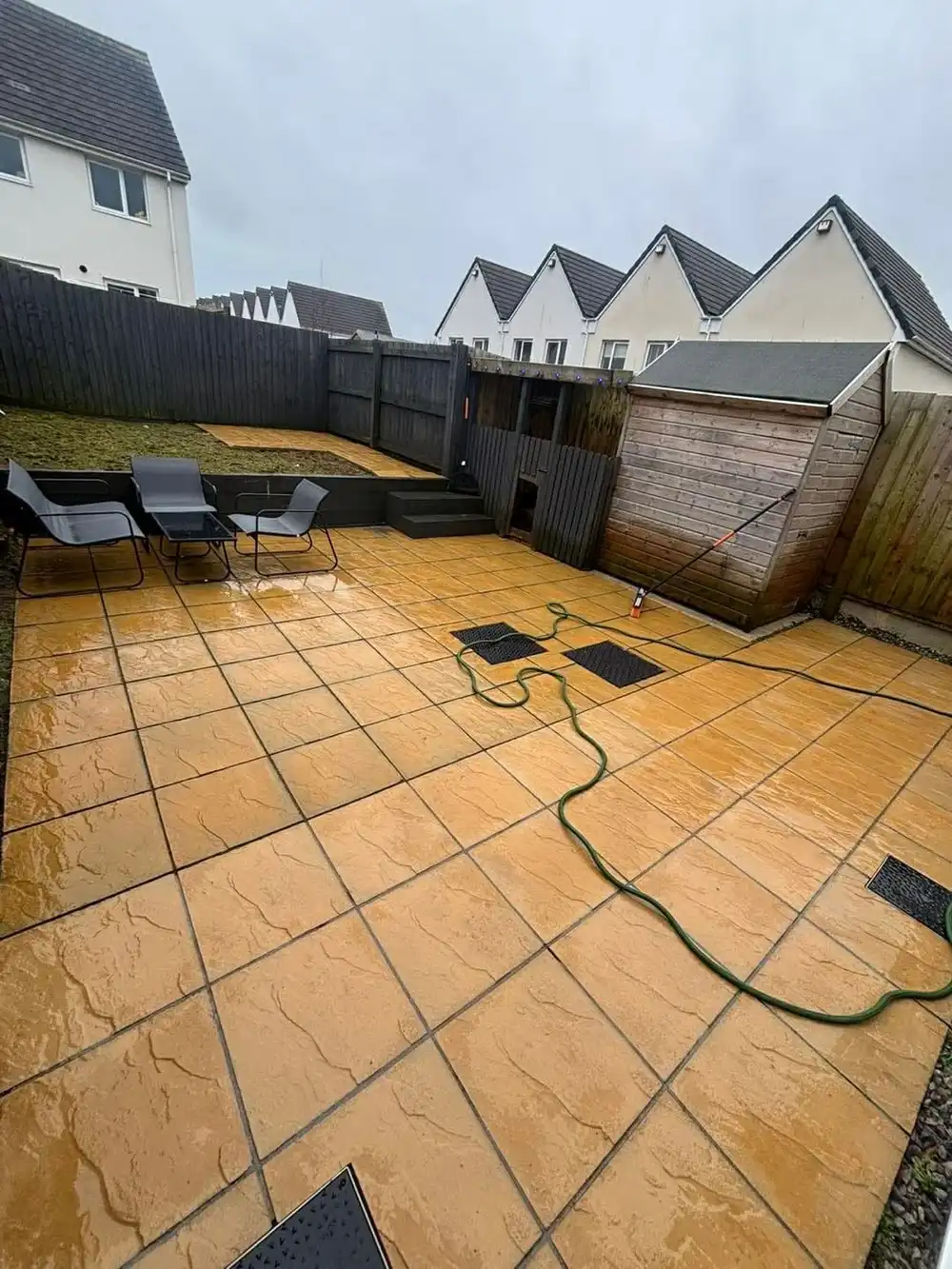 The same patio washed clean and wet down, the joints clear and the colour of the slabs showing again