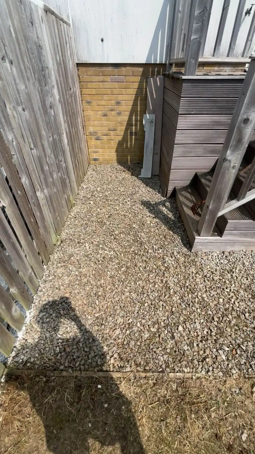 The same corner of the yard emptied and finished with a clean bed of fresh gravel